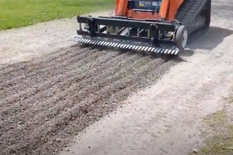 an orange construction truck working on a gravel driveway