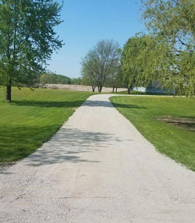 a long gravel driveway in between to green grass lawns