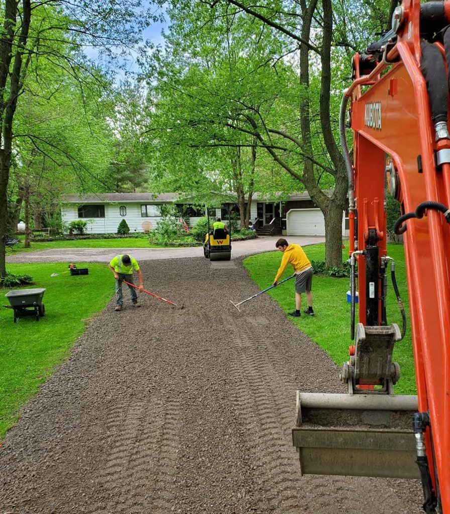 two men working outside using rakes on a new gravel driveway
