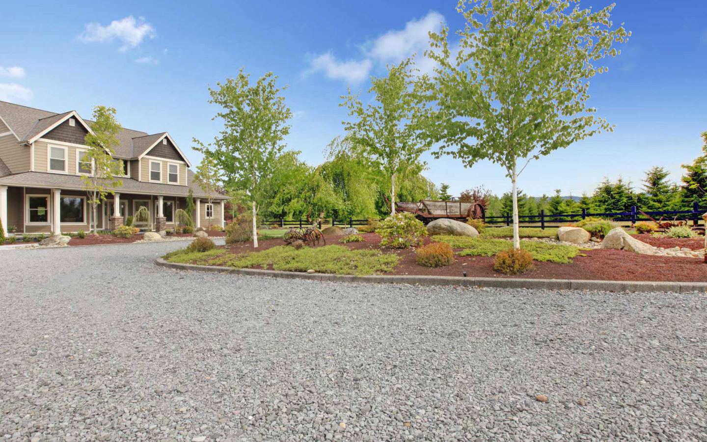 blue gravel drive in foreground with large double story house towards the left