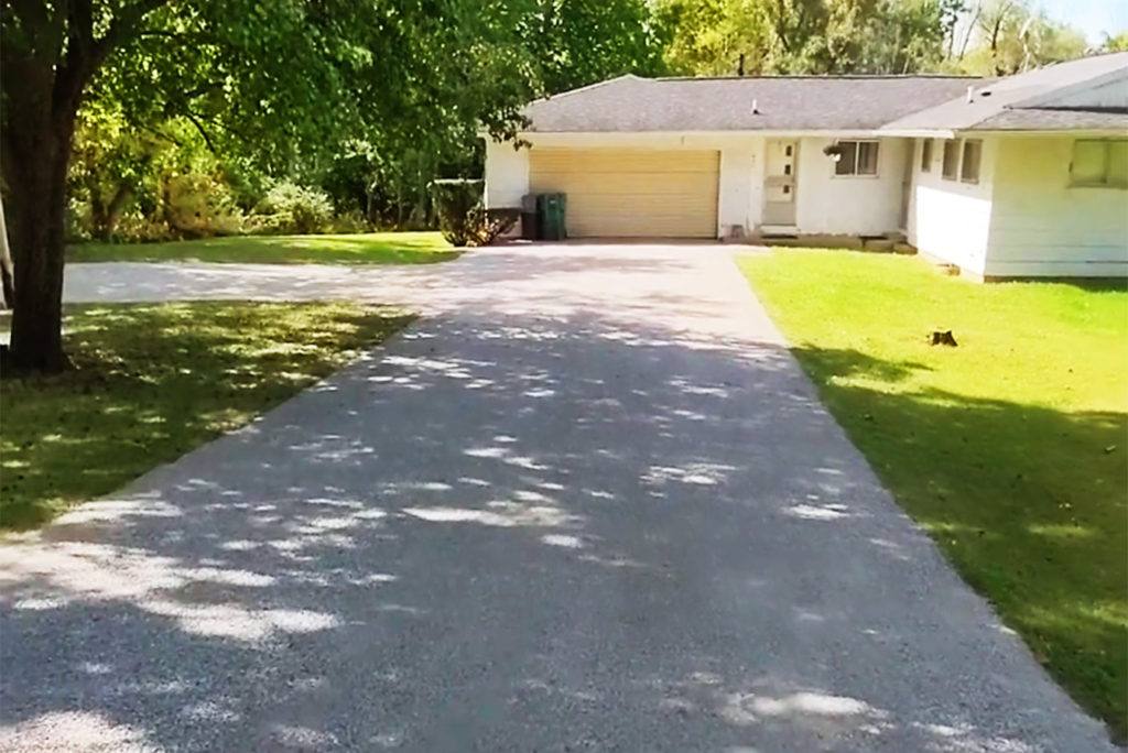 a gravel drive leading to a closed garage