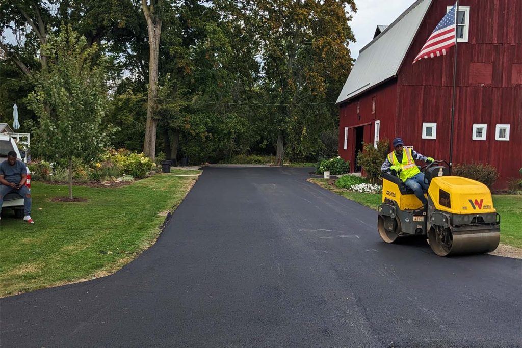 a man on a roller flattening an asphalt drive