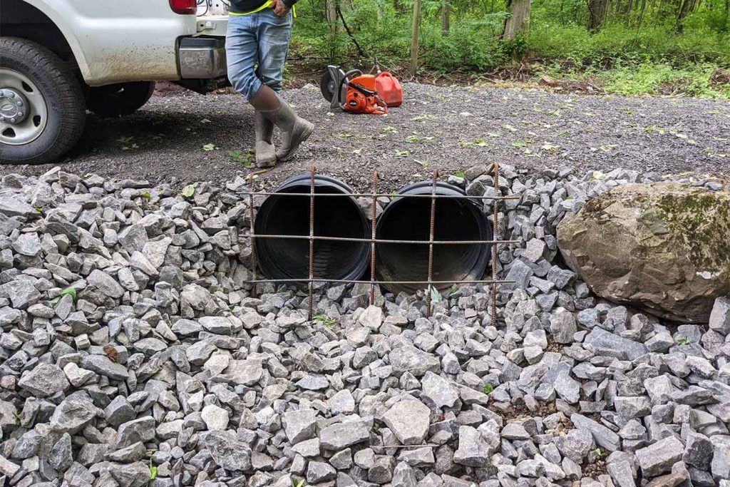 two culvert pipes passing under a gravel road