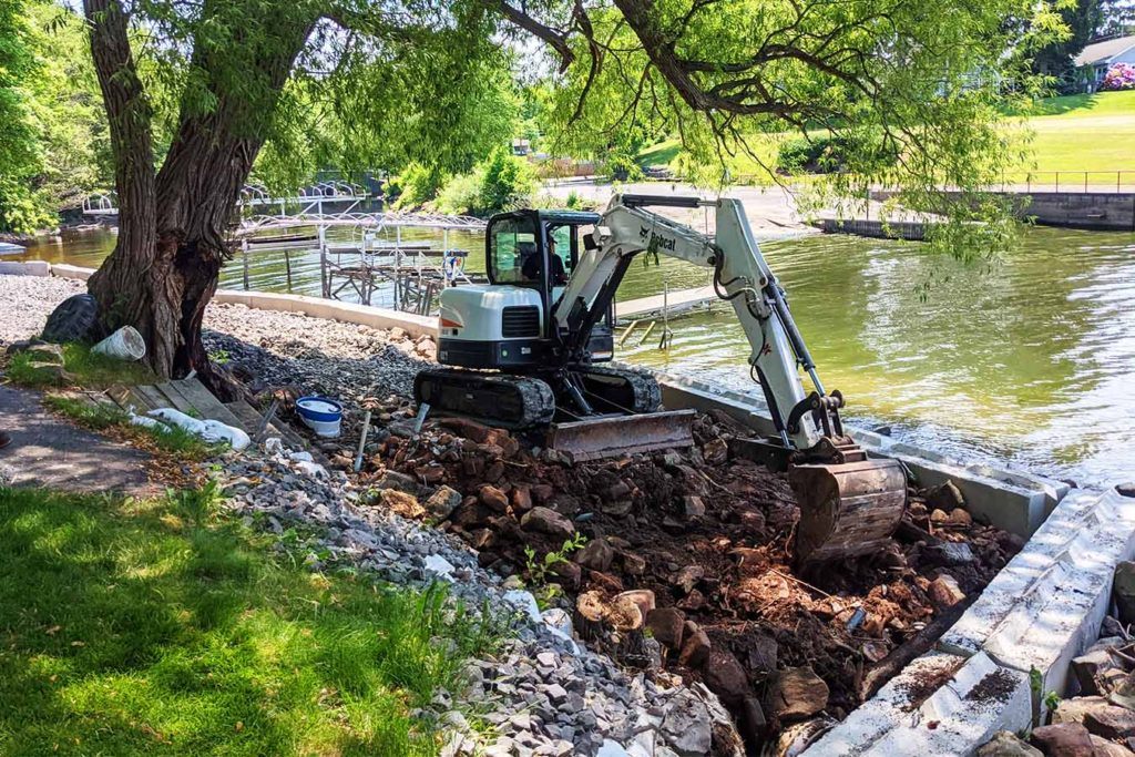 a JCB digging a trench next to a waterway