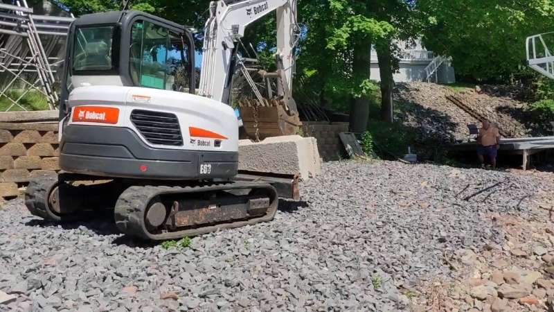 The excavator carrying the concrete block to the desired location